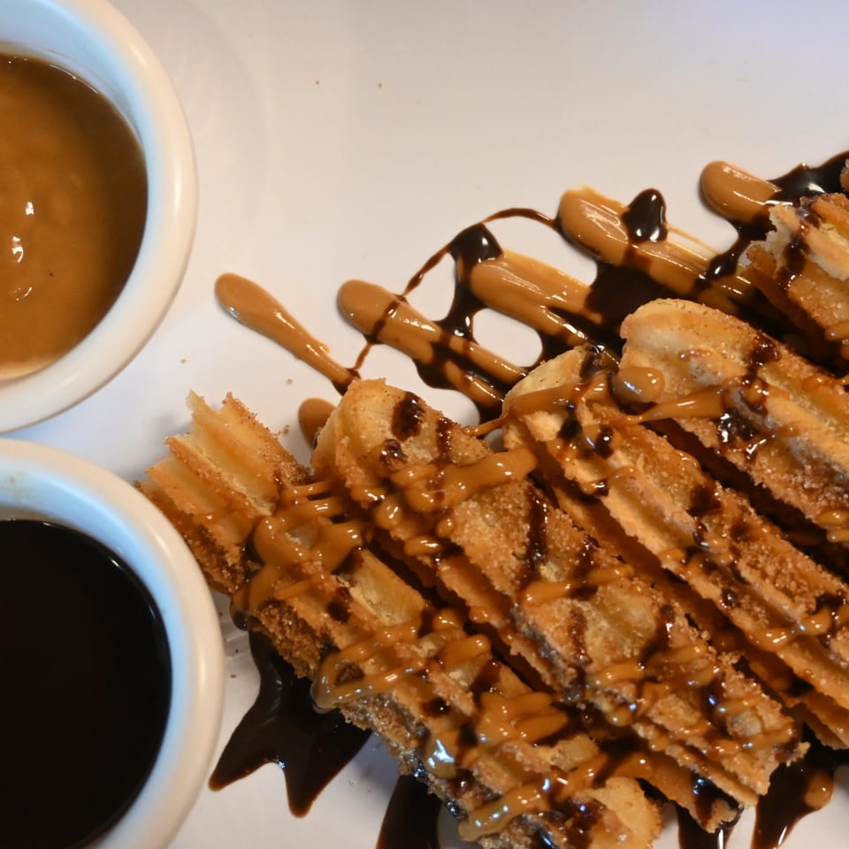 Churros drizzled with chocolate and caramel sauces, served with two dipping sauces.