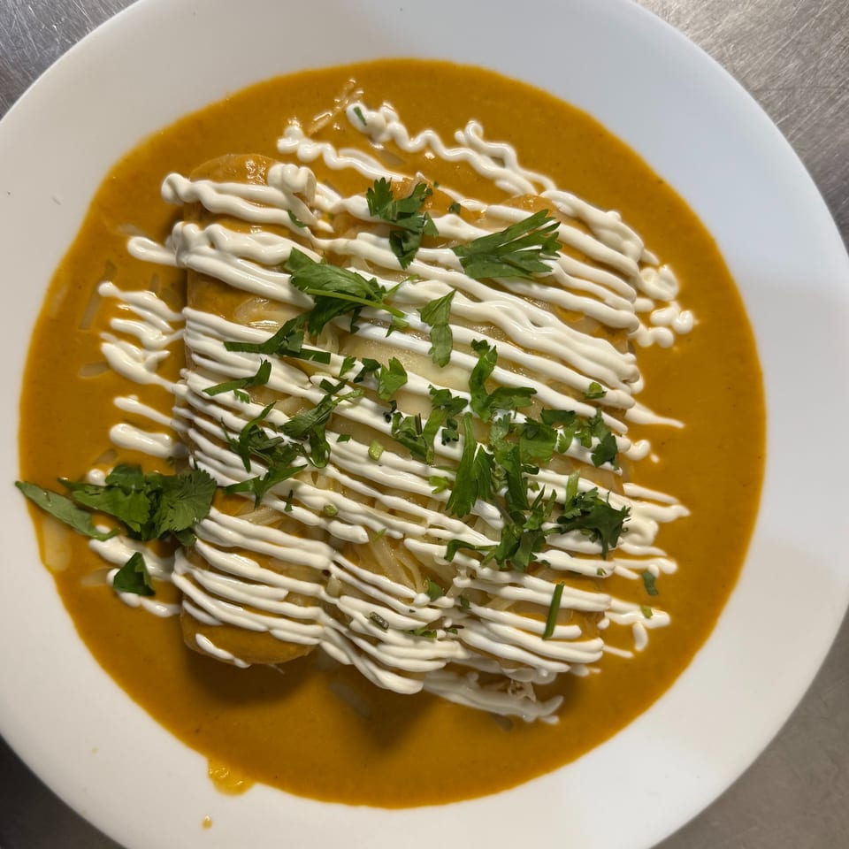 La Reyna Xpress enchiladas in a rich orange sauce, drizzled with white cream and fresh cilantro.